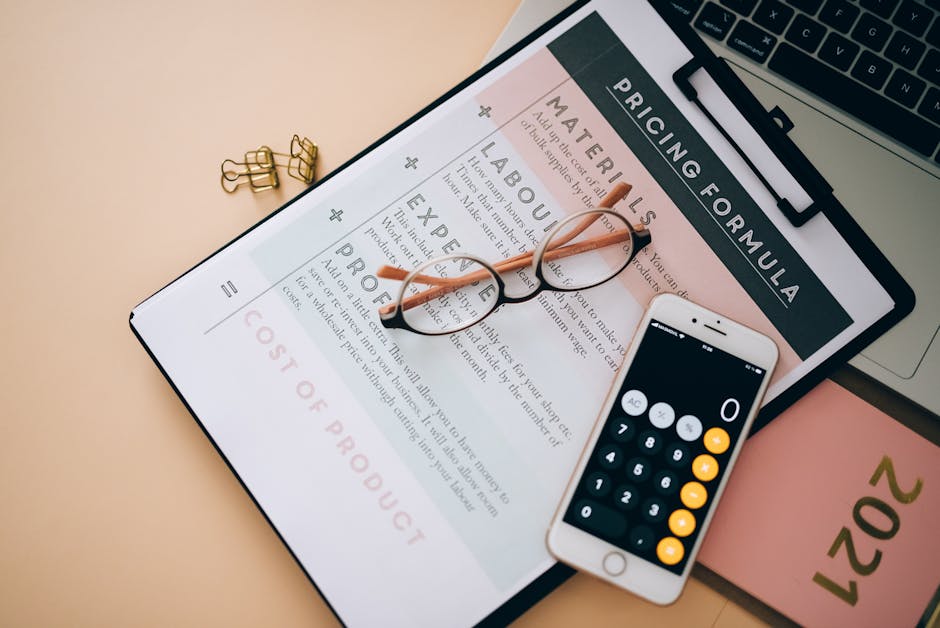 A digital tablet displaying a pricing form with sections for materials, labour, and expertise, positioned on a light beige surface. Resting on the tablet are a pair of black-rimmed eyeglasses and a wh